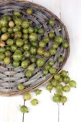 Green gooseberry on wicker mat on wooden background