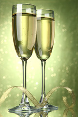 Two glasses of champagne on bright background with lights