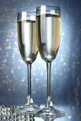 Two glasses of champagne on bright background with lights