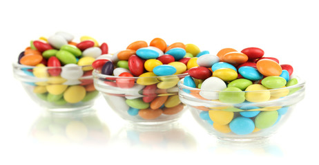 Colorful candies in glass bowls isolated on white