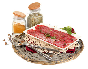 Tasty salami on plate on  wicker cradle isolated on white