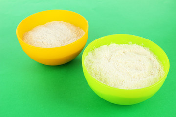 Powdered milk in bowls for baby on green background