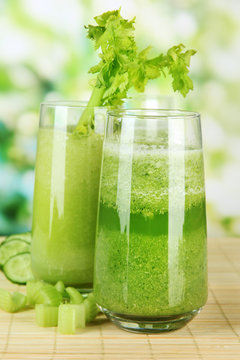 Glasses of green celery juice on bamboo mat, on green