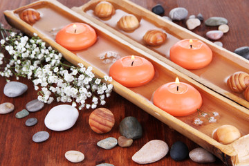 Beautiful candles in water on wooden table close-up