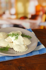 Tasty dumplings on plate, on wooden table