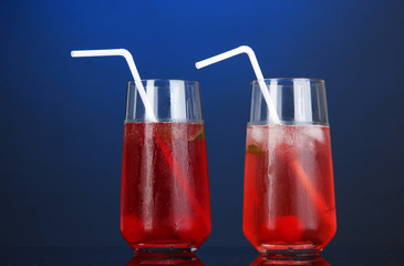 Two cherry cocktails with ice on dark blue background