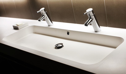 Fototapeta premium Modern white sink with two shining faucets, tap and soap