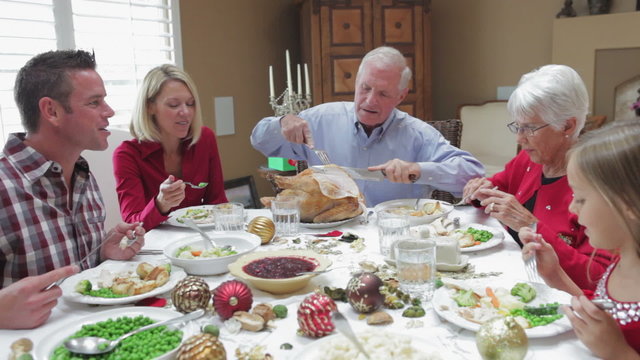 Grandfather Carving Turkey At Family Thanksgiving Meal