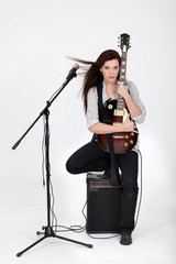 Musician hugging her guitar and posing with her equipment