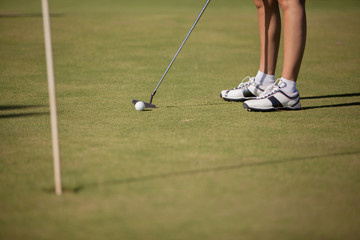 Female golfer playing in the green. Focus on Golfer.