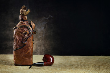 Leather vintage bottle with a pipe on a dark background