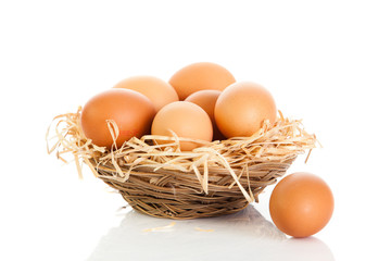 Brown eggs in the basket on white.