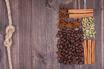 Coffee beans, cinnamon, star anise, cardamom on wood background