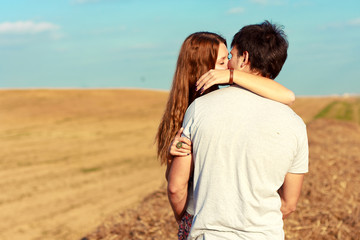 Young attractive couple in love kissing in summer in field