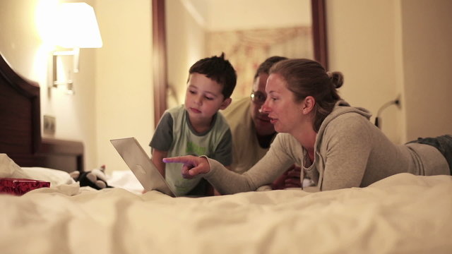 Happy family with laptop lying on bed, steadicam shot