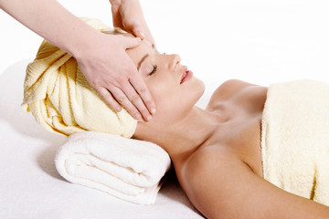 Young pretty woman laying down and receiving face massage