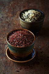 Red, brown and wild rice in ceramic dishes