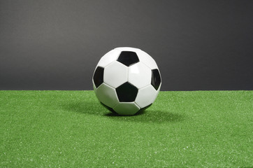 Balón de fútbol y césped artificial, fondo negro
