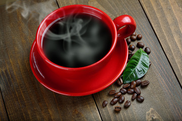 cup of fresh coffee with coffee beans on wooden table