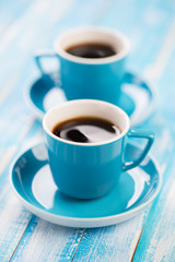 Vertical shot of two turquoise espresso cups on wooden boards