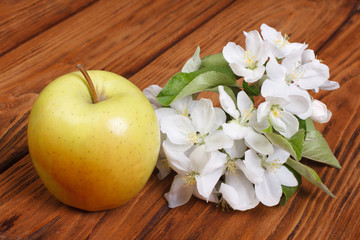 Whole green apple with flowers on wooden table