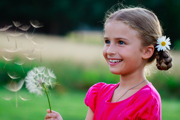 Summer joy - lovely girl blowing dandelion