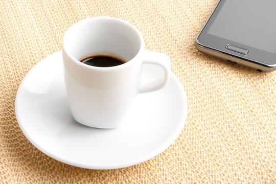 dark espresso in a cup near smartphone