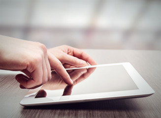 white tablet with a  blank screen in the hands on table
