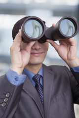 Fototapeta na wymiar Young businessman looking through binoculars, Beijing
