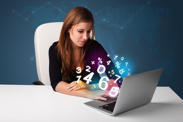 Beautiful young woman sitting at desk and typing on laptop with