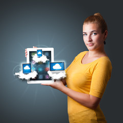 young woman holding tablet with modern devices in clouds
