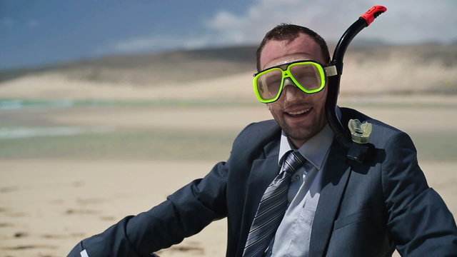 Happy businessman in diving mask on the beach
