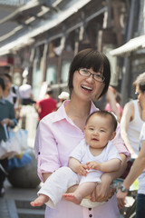 Naklejka premium Portrait of mother holding her baby son, outdoors Beijing