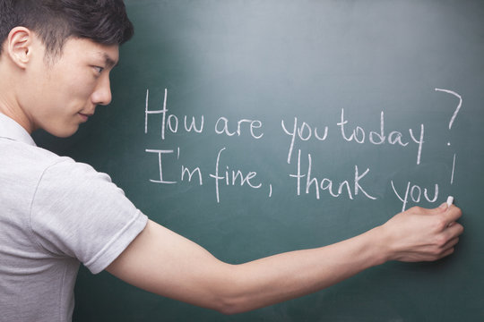 Young Man Writing English Sentences On The Blackboard