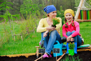 Gardening, planting - girl helping mother in the garden