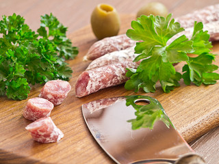Salami aufgeschnitten auf einem Holzbrett mit Oliven.