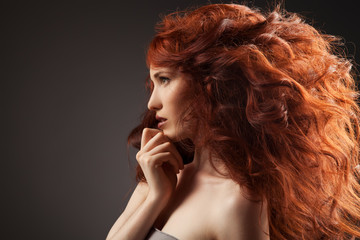 Beautiful woman with curly hairstyle against gray background