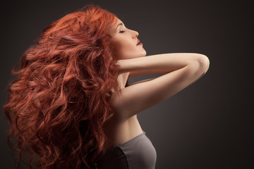 Beautiful woman with curly hairstyle against gray background