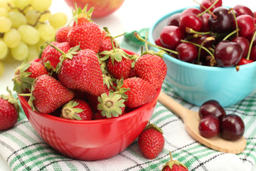 Ripe strawberries and cherry berries in bowls, grapes and apple