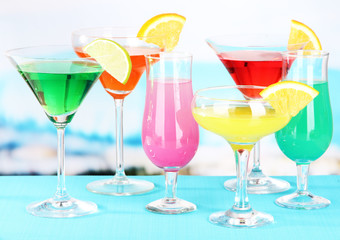 Glasses of cocktails on table near pool