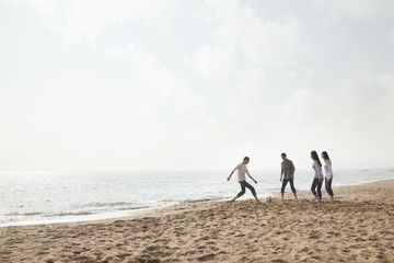 Fototapeta na wymiar Young Friends Playing Soccer on the Beach