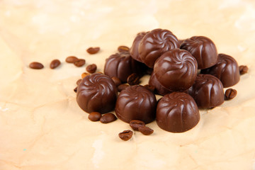 Chocolate candies and coffee beans, on beige paper background