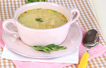 Nourishing soup in pink pan on wooden table close-up