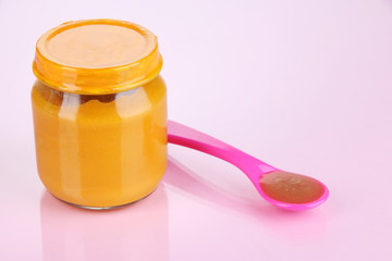 Baby food with weaning spoon on purple background