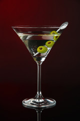 Martini glass with olives on dark red background