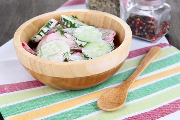 Vitamin vegetable salad in wooden bowl on wooden table close-up