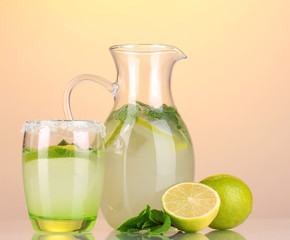 Lemonade in pitcher and glass on yellow background