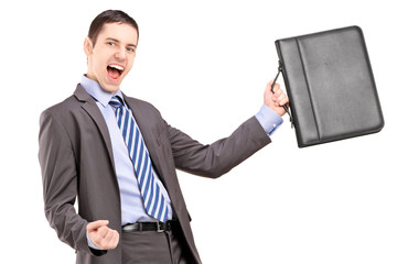 A happy young businessman holding a briefcase and gesturing happ