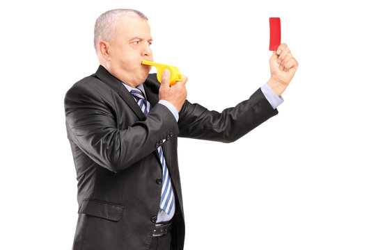 A Mature Businessman Blowing A Whistle And Showing A Red Card