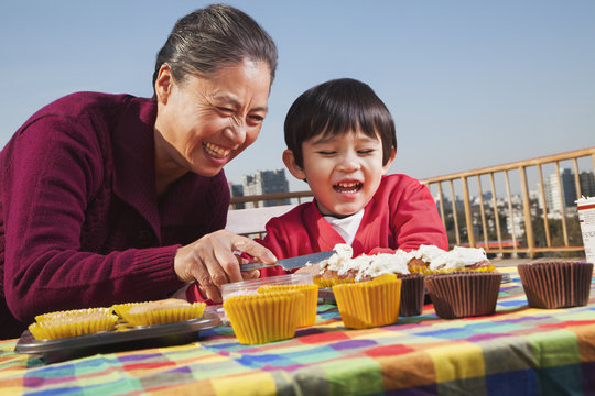 Grandmother and grandson decorating cupcakes  - Powered by Adobe